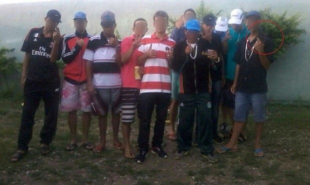 Grupo reunido para foto; à direita, suspeito exibe uma arma  (Foto: Divulgação/Polícia Civil)