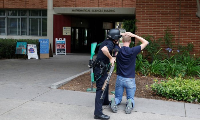 Policial revista estudante no campus da UCLA, em Los Angeles. Duas pessoas morreram em tiroteio na universidade - PATRICK T. FALLON / REUTERS